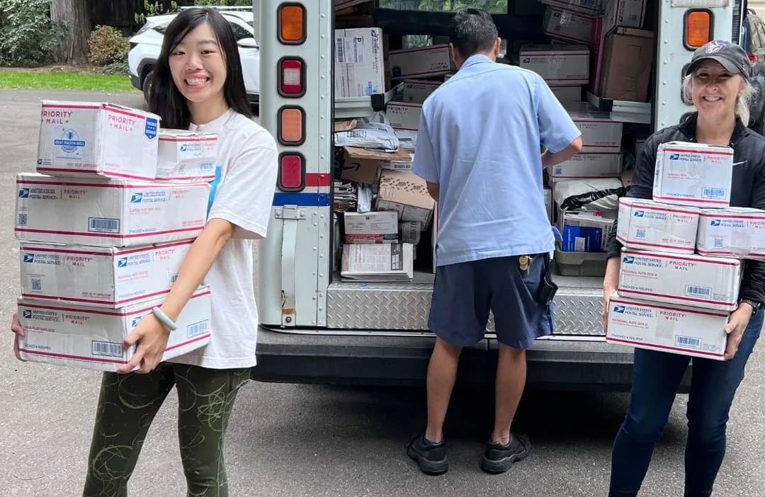 People holding USPS boxes at a mail truck, ready to send nesting blocks back