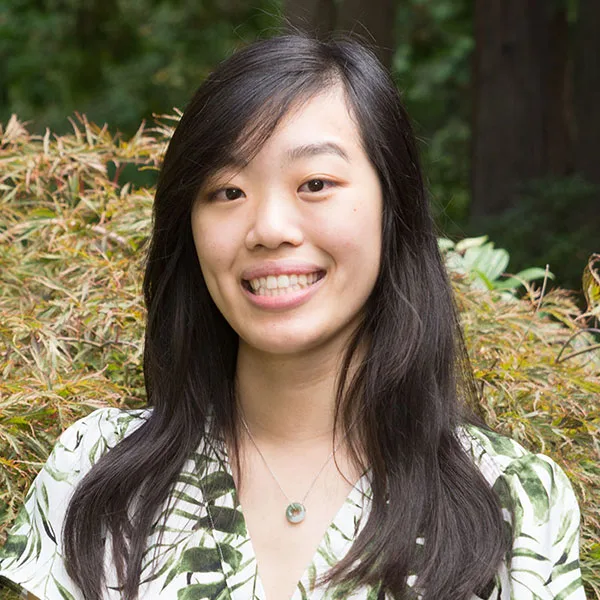 Portrait of Nina Tran outdoors, in front of green shrubs