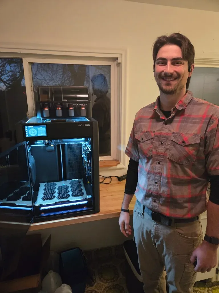 Kelton Watts beside a 3D printer making Bee Shield plates