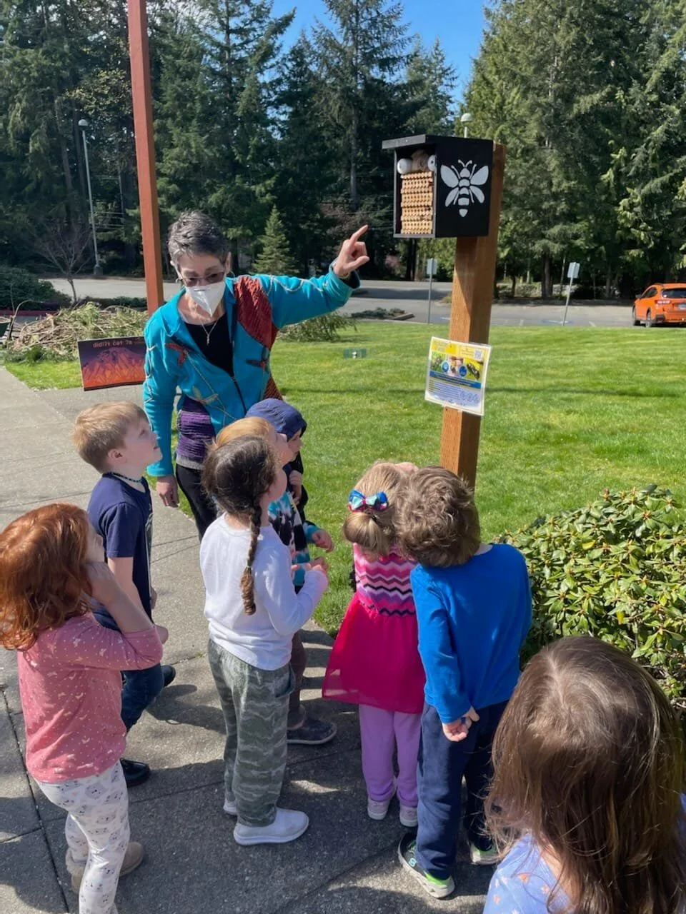 Children gathered around a mason bee house with an educator