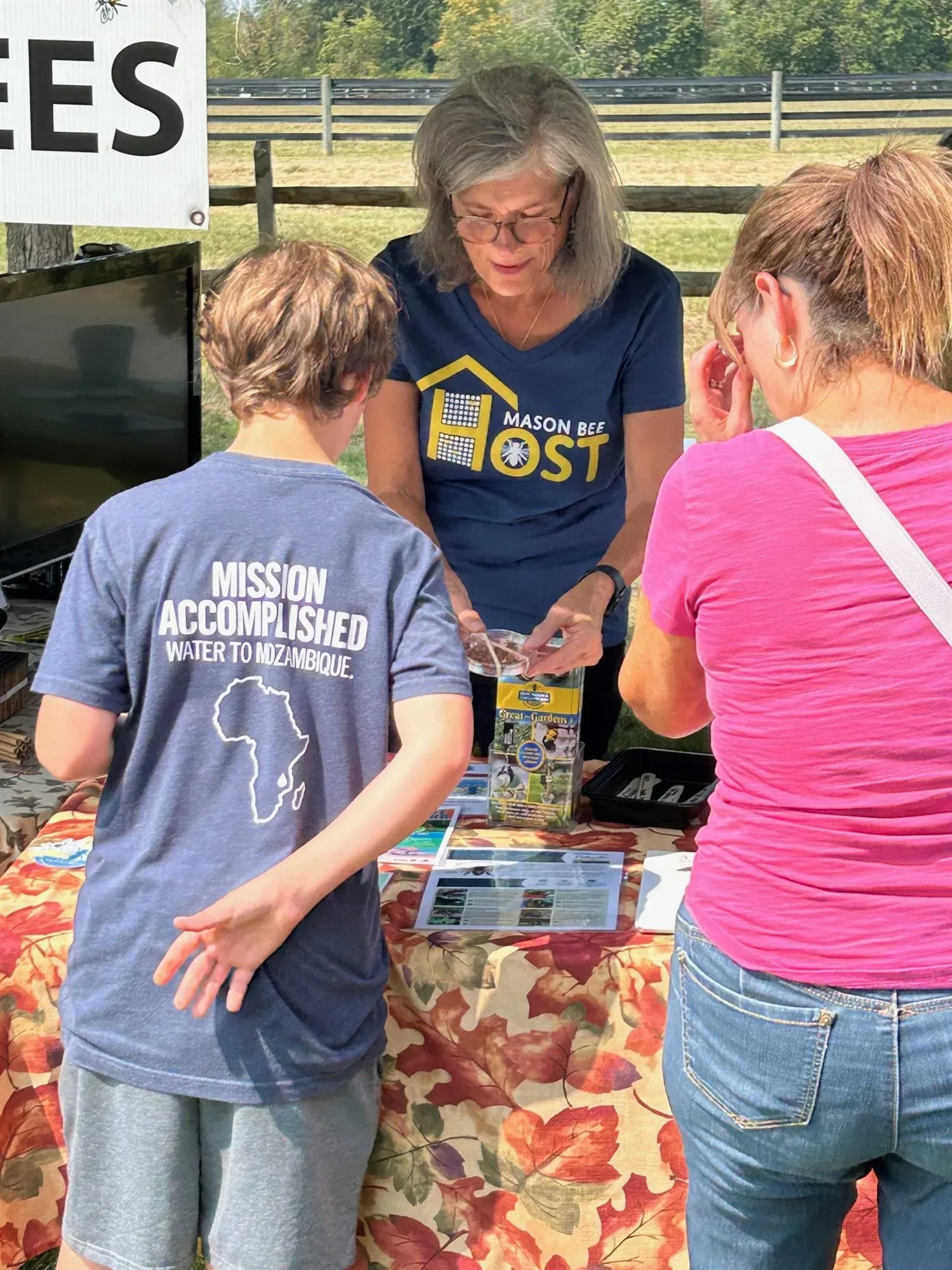 A host showing a nesting block to a child and an adult at a booth