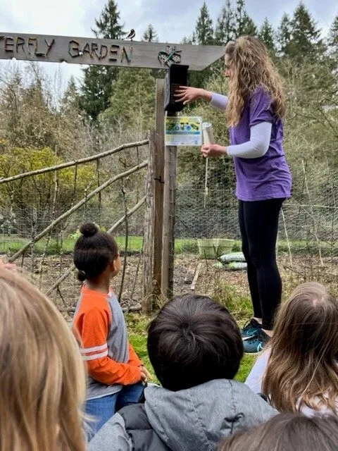 A teacher showing a mason bee house to children in a garden